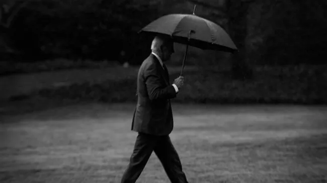 Joe Biden walks with an umbrella